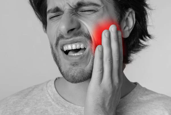 man experiencing pain on his jaw, gums, or teeth; man needs emergency dental care