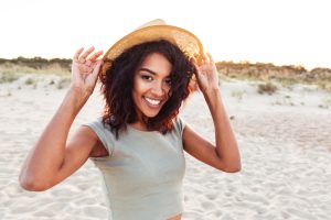 young lady holding her hat on the windy beach