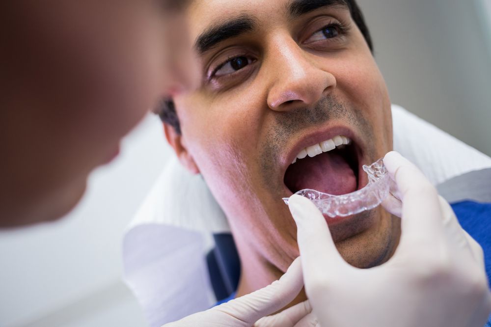 a dentist is checking if a dentures fits on a man's face or not