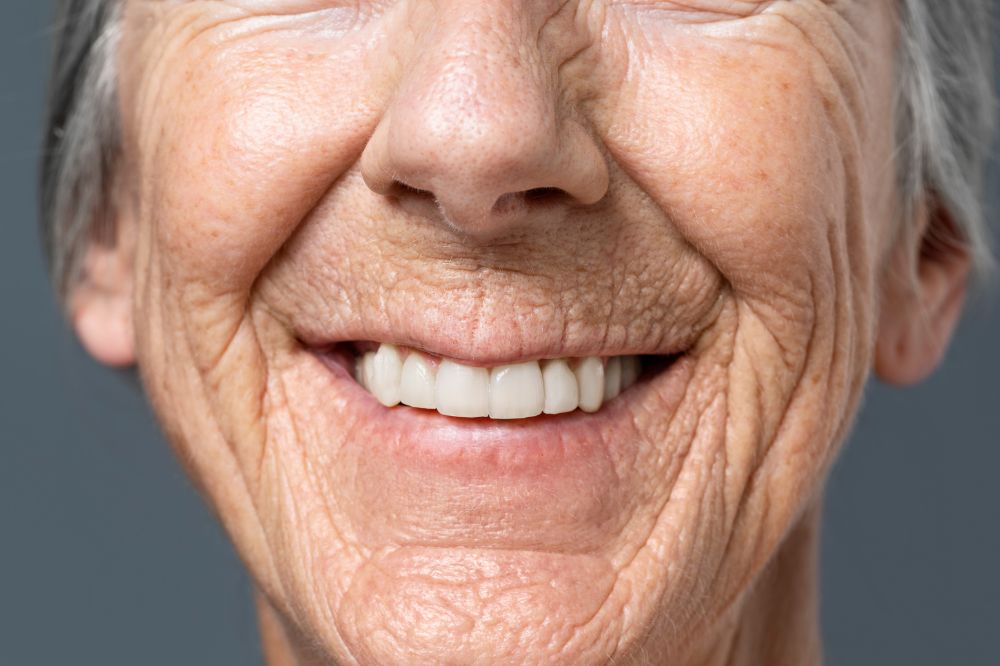an old woman is smiling after putting dentures
